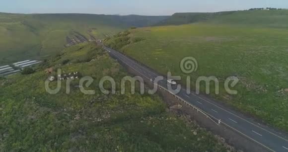在以色列北部的戈兰高地和泰伯里亚上空的空中射击在绿油油的空地上行驶的车道视频的预览图