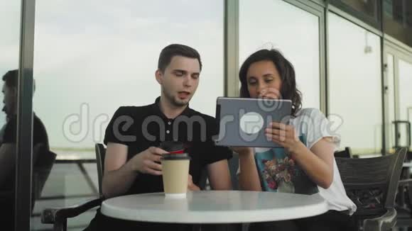 在城里的咖啡馆里玩平板电脑的情侣视频的预览图