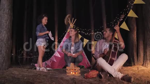家庭互动快乐的父母与他们的女孩子在树林里玩火带着吉他背景视频的预览图