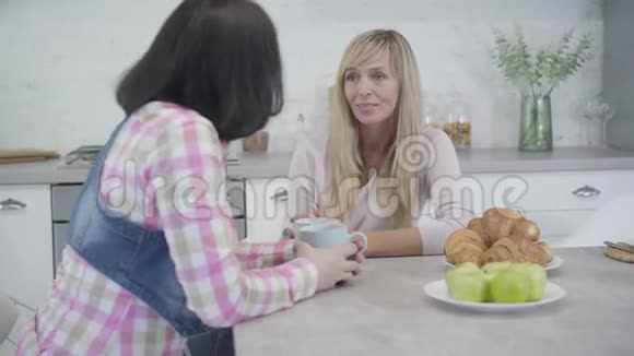 一幅金发白种人女人和朋友坐在桌子旁聊天的肖像两个成年女人闲聊喝酒视频的预览图