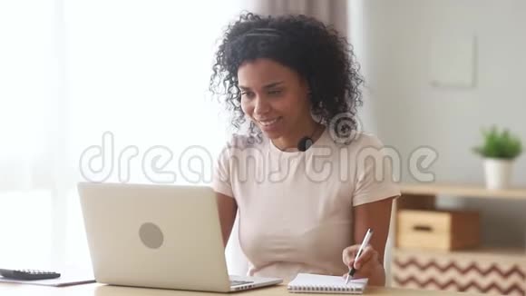戴耳机的混血女人在网上学习笔记视频的预览图