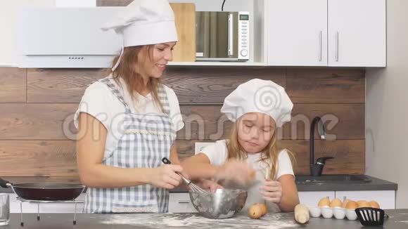 家庭观念年轻的白种人母亲教她的孩子烘焙烹饪视频的预览图