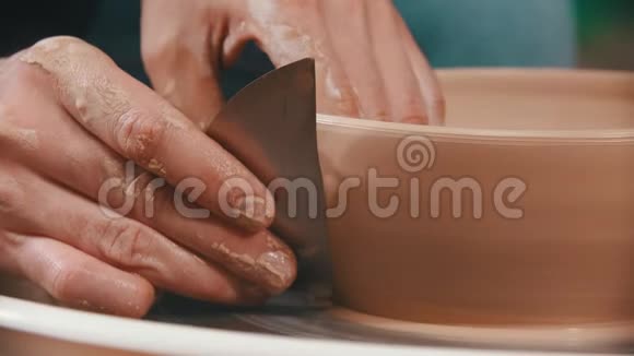 陶器主人正在帮助一个特殊的金属刮刀以平滑粘土碗的表面视频的预览图