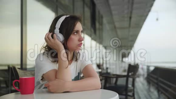 漂亮的年轻女性带智能手机的耳机听音乐视频的预览图