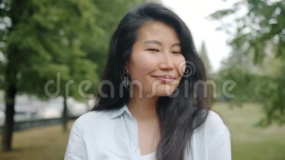 可爱的亚洲女孩微笑着调情看着夏天公园里的摄像机视频的预览图