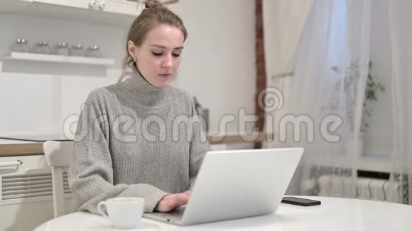 放松的年轻女性喝咖啡在笔记本电脑上工作视频的预览图