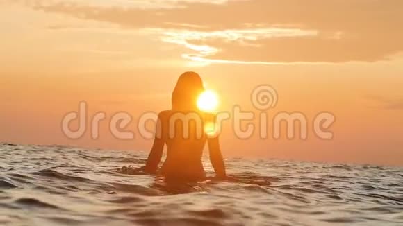 一个女人从水中翻滚而出的剪影在黎明时起的起的的头发围成一个圆圈一个女孩在游泳视频的预览图
