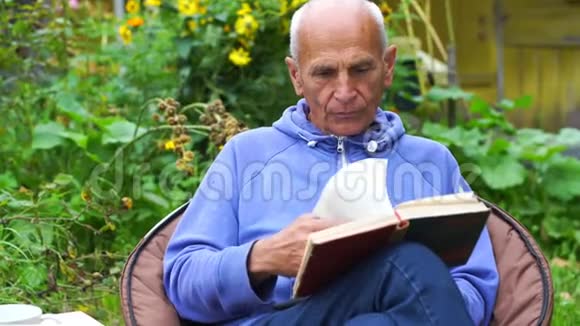 老人坐在院子里拿着鲜花翻书视频的预览图