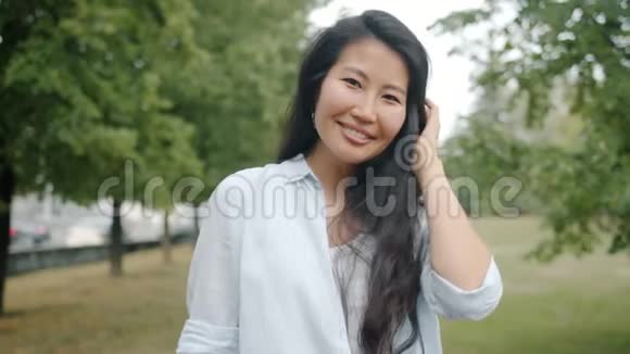 在公园调情的亚洲学生抚摸着头发微笑着看着镜头视频的预览图