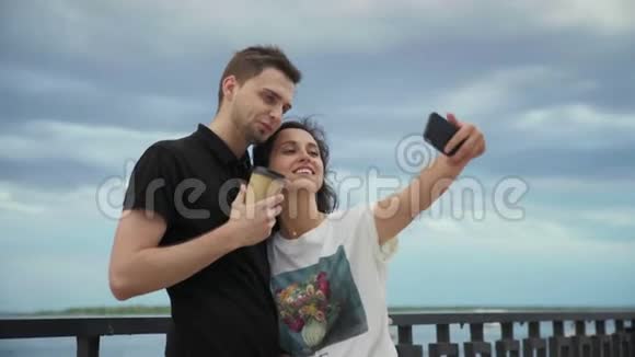 恋爱中的浪漫幸福情侣在海边打电话拍照视频的预览图