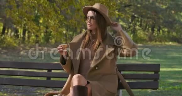 美丽的高加索女人戴着太阳镜和优雅的衣服喝着茶或咖啡环顾四周美丽美丽视频的预览图