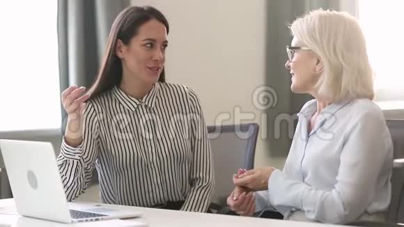不同年龄的女商人坐在办公桌前讨论商业问题视频的预览图