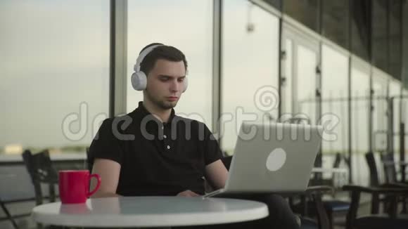 年轻人坐在咖啡馆里用笔记本电脑看喜剧电影视频的预览图