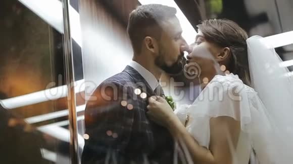 新郎和新娘在电梯里接吻新婚夫妇在拥抱一个女孩拉着一个男人的夹克给自己婚礼视频的预览图