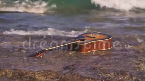 波浪把吉他扔在空岸或石滩上潮把吉他带上岸吉他游泳游泳漂流漂浮视频的预览图