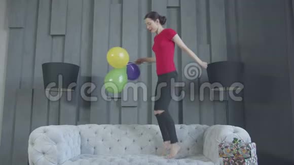 兴奋的生日女孩在家沙发上跳视频的预览图