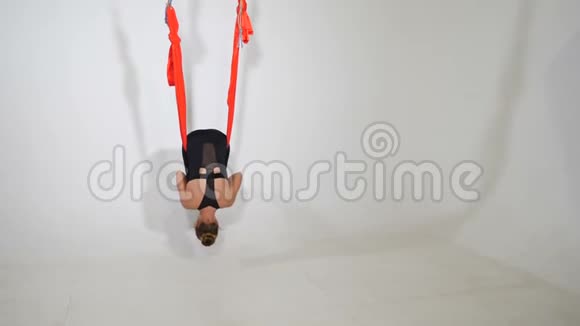 有魅力的运动女性在带有白色墙壁的吊床运动俱乐部练习重力瑜伽一位美丽的女士视频的预览图