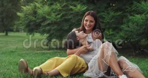 吸引人的是公园里的两位女士她们一起坐在草地上笑嘻嘻地在旁边聊天视频的预览图