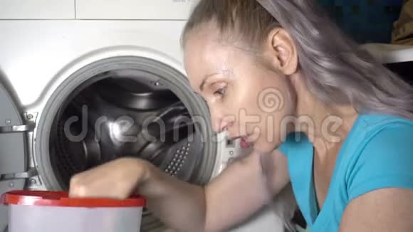 年轻的女人准备在洗衣机里洗用洗衣粉打开盒子情绪上回应了这样一个事实视频的预览图