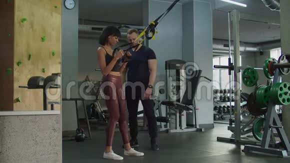 女性在健身房运动时使用TRX健身带视频的预览图