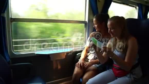 女孩们看着小册子在火车上谈论路过的风景视频的预览图