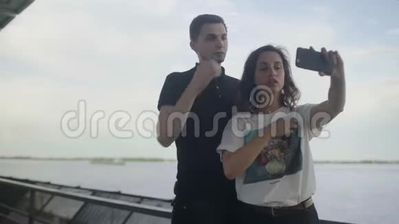 有趣的一对恋爱中的年轻夫妇在河边拍照视频的预览图