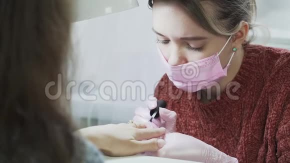 穿粉色医用口罩和手套的女孩不会淘汰客户指甲护理美容院视频的预览图