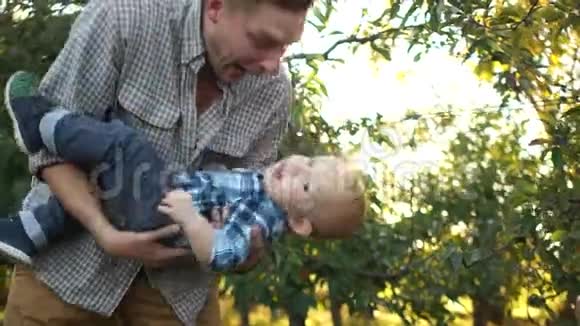 年轻的父亲和他的小儿子在夕阳下的花园里玩得很开心多代家庭父亲节视频的预览图