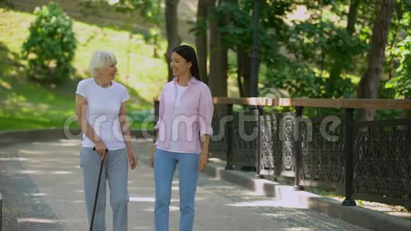 孙女在公园里用棍子走路与老妇人交谈老年健康视频的预览图