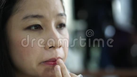 亚洲女人化妆时用手指在嘴唇上涂唇膏霜视频的预览图