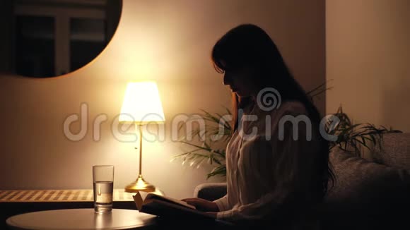 集中精力的年轻女人读一本书从杯子里喝一口水视频的预览图