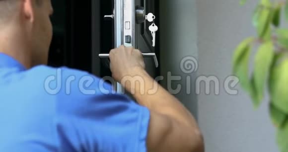 穿蓝色制服的锁匠安装新房门锁视频的预览图