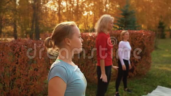 舞女在秋季公园训练舞蹈健身妇女在城市公园的户外课上跳舞瑜伽团体视频的预览图