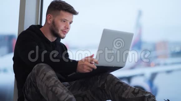 一个人坐在机场用手提电脑上班背景模糊的飞机视频的预览图