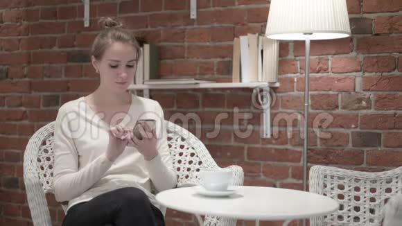 喝咖啡庆祝智能手机成功的女人视频的预览图