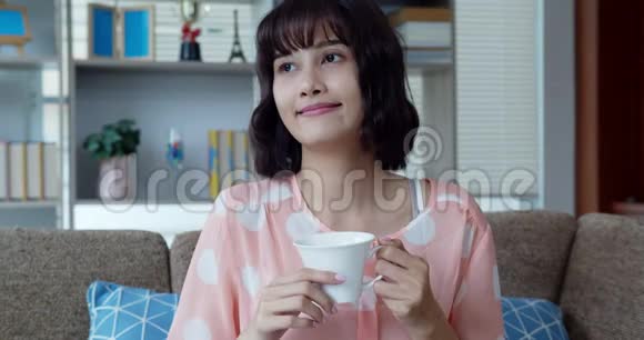 亚洲漂亮的年轻女人喝热咖啡时很开心视频的预览图