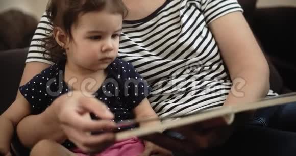 一位年轻的母亲和她蹒跚学步的孩子一起读一本书视频的预览图