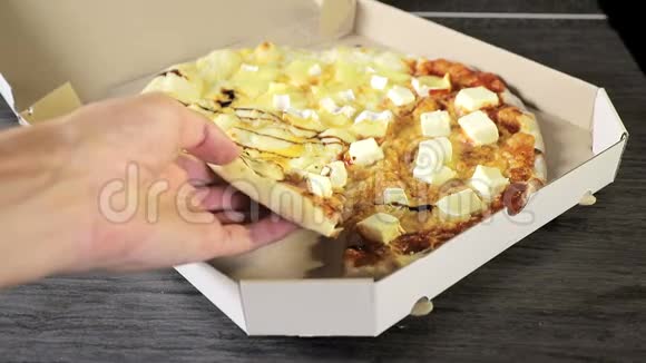 从白色纸板箱里拿出一片比萨饼的特写手拿着一片披萨四个奶酪视频的预览图