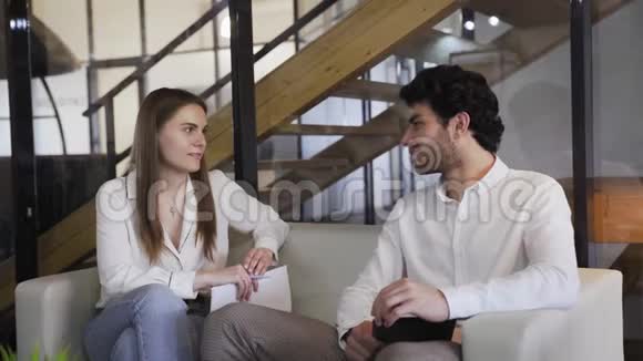 年轻优雅的夫妇坐在白色沙发上聊天视频的预览图