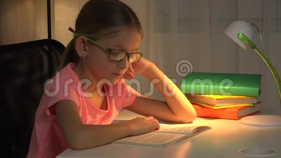 带眼镜的儿童读物在台灯学习的女孩4K视频的预览图