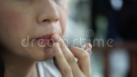 亚洲女人用手指在嘴唇上涂唇膏做化妆视频的预览图
