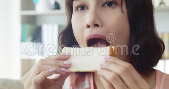 年轻女人咬着吃一个大三明治和美味视频的预览图