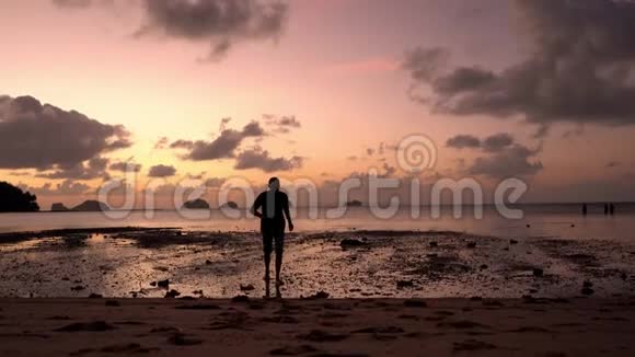 日落时在海滩上剪影的家伙热带的日落那家伙高兴地从水里跑出来视频的预览图