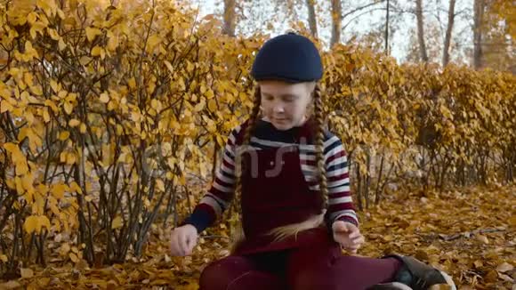 可爱的少年女孩红头发辫在秋天的公园里扔黄叶快乐的女孩把落叶从视频的预览图