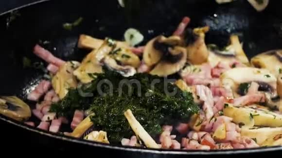 细碎的火腿大蒜蘑菇和菠菜用热油在锅里炒视频的预览图