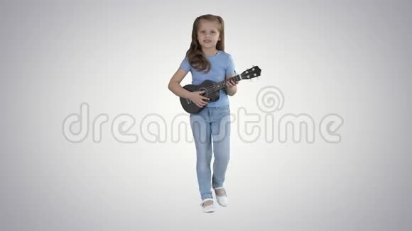 小女孩一边唱着小吉他一边在渐变背景下走向相机视频的预览图