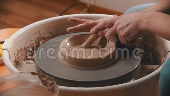 陶器主人用手指在陶工的轮子上做陶碗底部视频的预览图