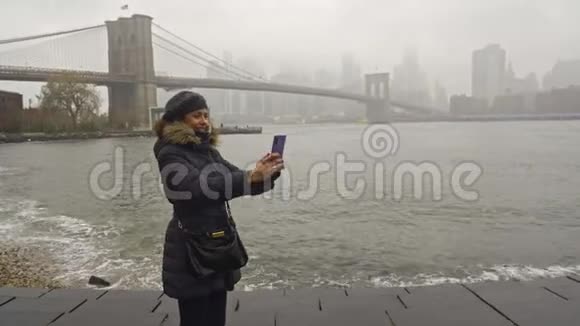 在布鲁克林大桥前美丽的卷发黑发女人自拍自画像视频的预览图