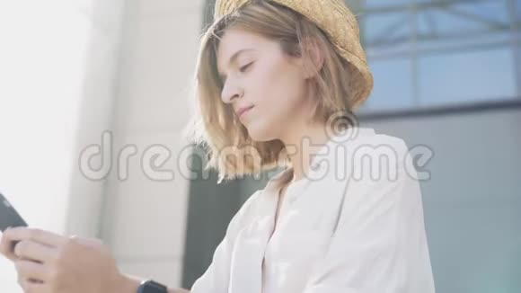 一个年轻漂亮的女人在城市公园里用手机开电动滑板车视频的预览图