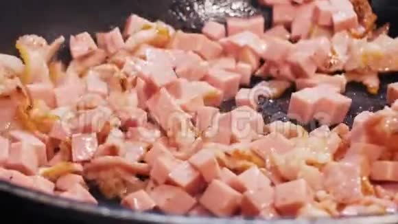 细碎的培根和香肠用热油在平底锅里煎视频的预览图